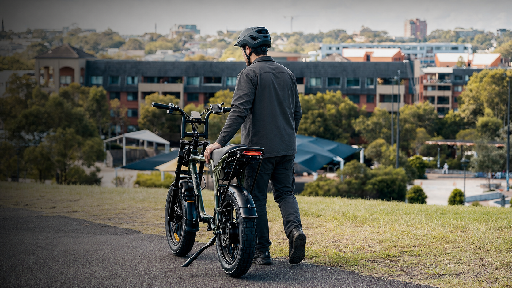 A rider walking with a Mamba electric bike overlooking the city.
